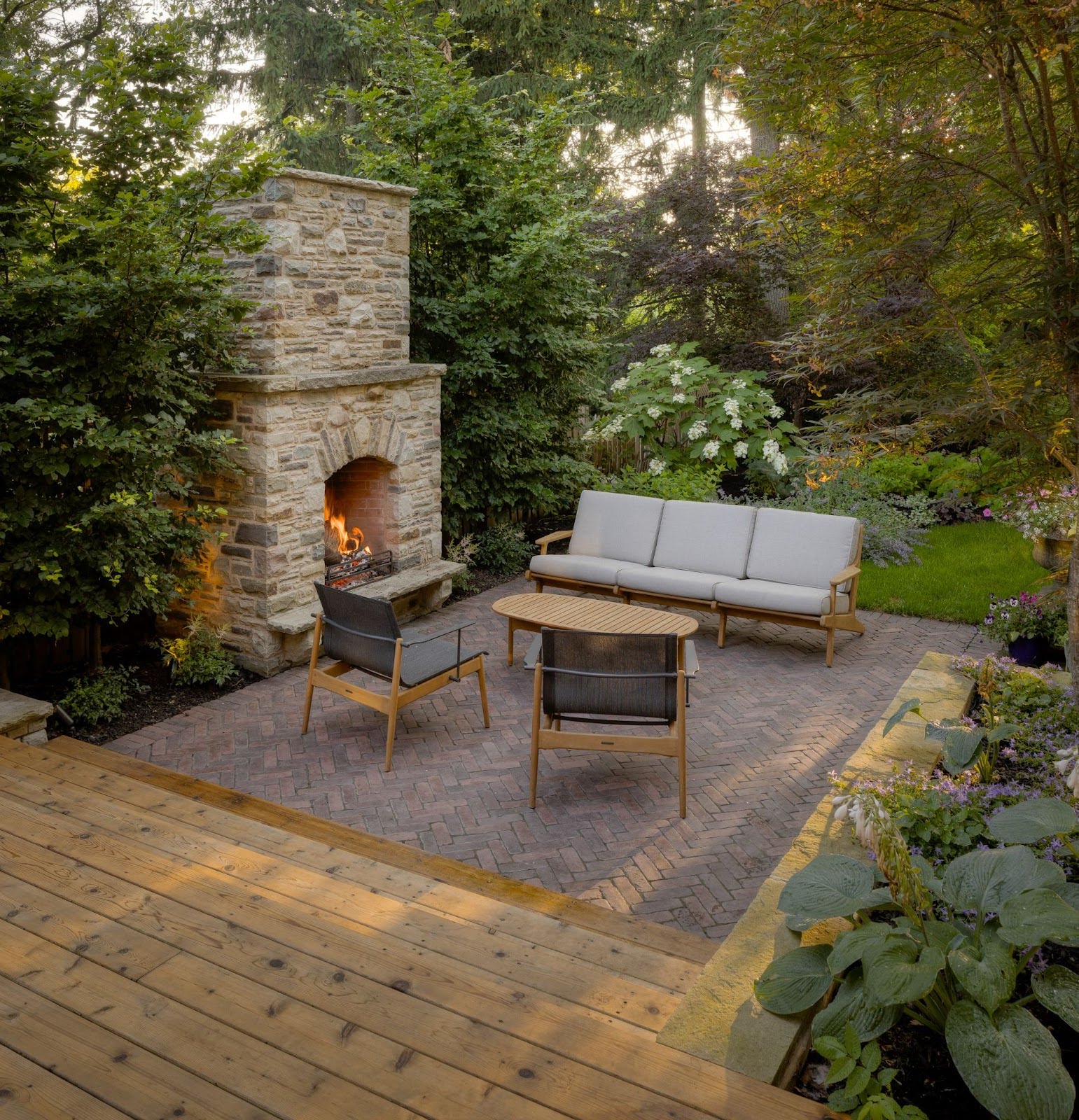 An outdoor fireplace made of stone next to a deck with patio furniture.